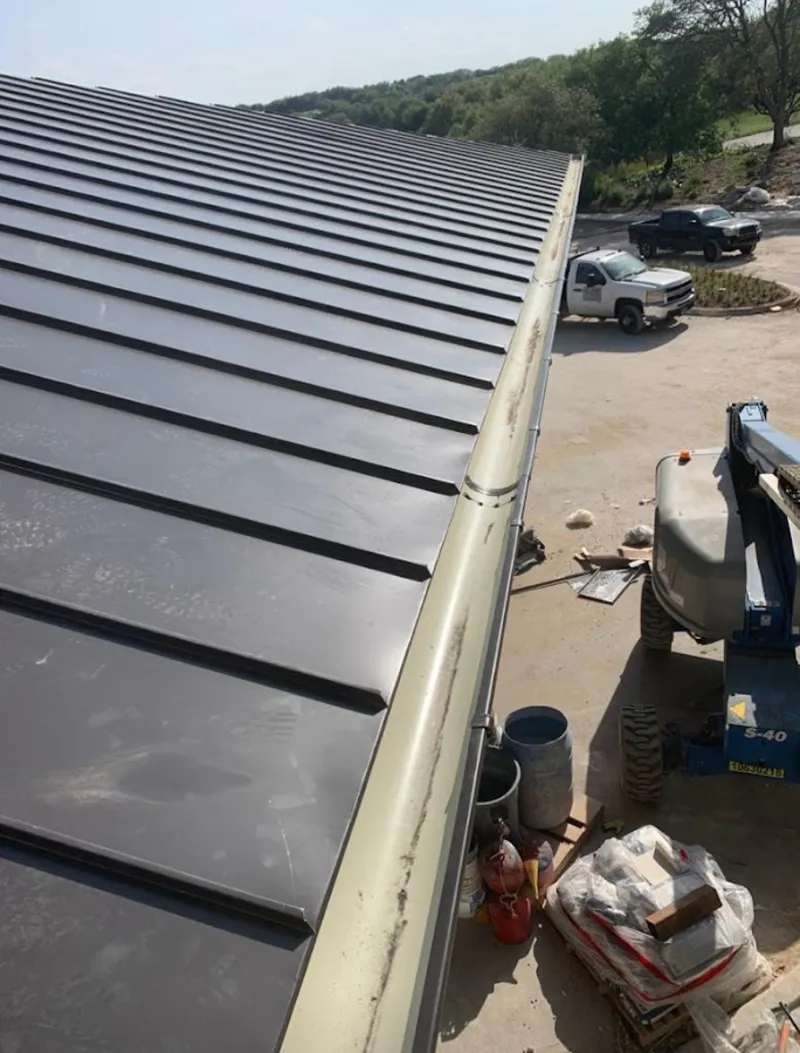 Standing seam panel and gutter detail on a metal roofing jobsite in Wilson